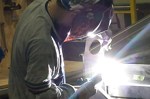 A single worker welding a piece of metal.